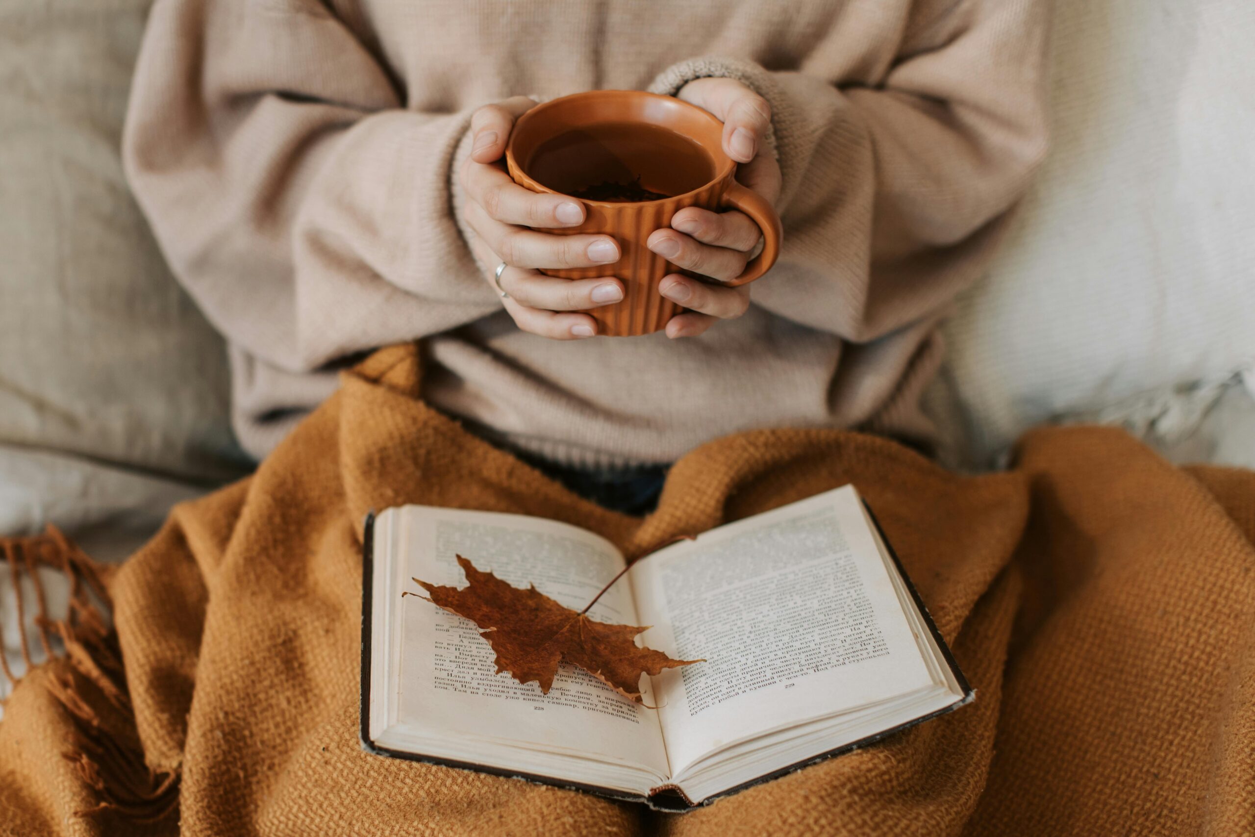 Жінка з чашкою чаю та книгою під пледом — інтроверт